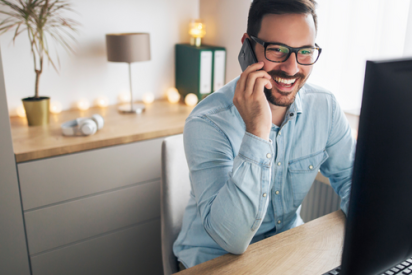 A man smiling on the phone while working from home