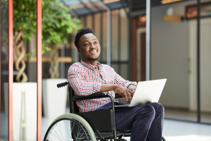 A man smiling in a wheelchair with a laptop