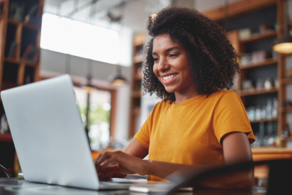 A young woman smiles at her laptop