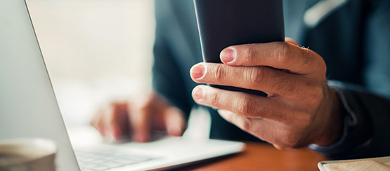 A professional working on a phone and laptop